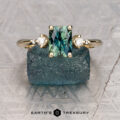 The "Selene" ring in 14K yellow gold features a 1.39-carat Australian sapphire and two round diamonds, shown on a rough blue stone. The Earth's Treasury logo appears below.