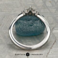 The "Alene" band in 14K white gold with an empty prong setting stands upright against a blue-green rough gemstone, with the Earth's Treasury logo visible at the bottom.