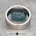 A platinum Linus Ring with a Montana sapphire is displayed balanced on a rough blue stone, with the text "Earth's Treasury" below.