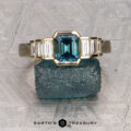The "Apollo" ring in 14K yellow gold with a 1.35-carat Montana sapphire is displayed on a rough crystal, with the "Earth's Treasury" logo below.