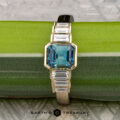 The "Apollo" ring features a 1.35-carat Montana sapphire set in 14K yellow gold, displayed elegantly on a green and silver background.