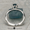 The "Ripple" ring in platinum, featuring a 1.23-carat Montana sapphire, is shown on a rough blue stone with a patterned gray background. "EARTH'S TREASURY" is displayed at the bottom.
