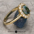 A "Stacked from 54 images. Method=B (R=1,S=3)" ring with a green-blue marquise gemstone and small diamonds rests on rough blue stone, set against a geometric metallic backdrop with the text "EARTH'S TREASURY.