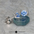 The EA-DB-402 earrings elegantly feature medium blue sapphires, each gemstone adding a sophisticated touch, beautifully set on a textured silver surface.