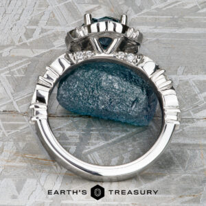 The "Stacked from 54 images. Method=B (R=1,S=4)" ring, featuring a striking blue gemstone and sparkling diamonds, stands upright on a rough blue stone against a textured background, radiating refined Paeonia elegance.