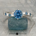The "Halia" ring in 14K white gold with a 1.12-carat Montana sapphire is displayed upright on a rough blue stone; Earth's Treasury logo appears at the bottom.