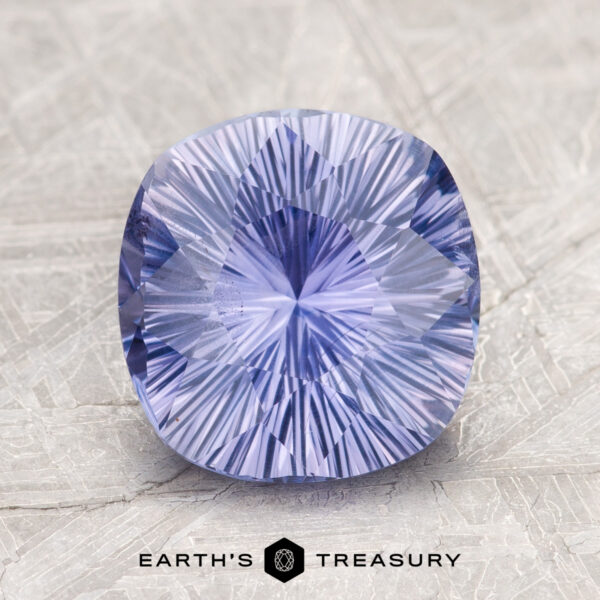 2.60-Carat Ceylon Sapphire A cushion-cut, radiant blue-purple gemstone displayed on a textured surface, labeled as "2.60-Carat Ceylon Sapphire" by Earth's Treasury below it.