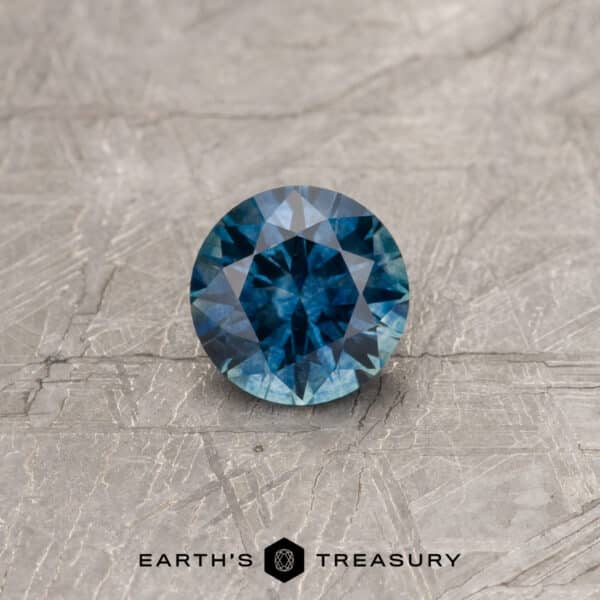 A blue-green Montana sapphire in a classic diamond round brilliant design