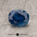 A 1.52-Carat Deep Blue Montana Sapphire (Heated) is shown on a textured gray surface with the "Earth's Treasury" logo at the bottom.