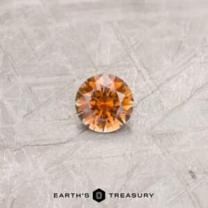 An orange Montana sapphire in a classic diamond round brilliant design