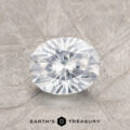 A 1.41-Carat Colorless Montana Sapphire with a round faceted cut rests on a textured gray surface, with the Earth's Treasury logo and text below.