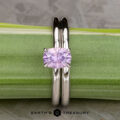 The "Fleur" ring in 14K white gold with a 1.06-carat Umba sapphire is shown upright next to a green plant stem, alongside its custom-fit straight band; the "Earth's Treasury" logo appears at the bottom.