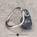 The "Minna" ring in 14K white gold featuring a 1.07-carat Montana sapphire sits on a rough blue stone atop a textured gray surface, with the "Earth's Treasury" logo displayed below.