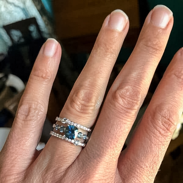 A photo from a customer review featuring a "Lamia" ring in 14k white gold with 1.12-Carat Montana Sapphire, alongside a custom double-band jacket