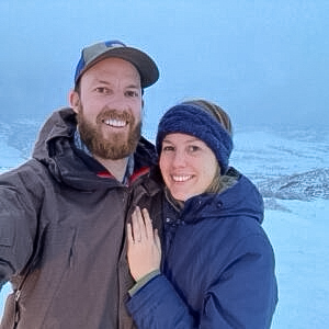 A photo from a customer review of a couple in the snow showing off their new engagement ring