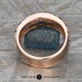 The Thin "Borealis" ring in 14k rose gold, featuring intricate detailing and a teal sapphire gemstone, is displayed upright on a textured gray surface above the Earth's Treasury logo.