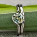A 1.54-carat Montana sapphire "Milos" ring in platinum, paired with the Custom-Fit Contour Band in platinum, showcased against a green background.