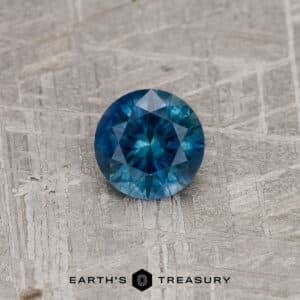 A blue-green Montana sapphire in a classic diamond round brilliant design