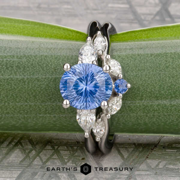 The "Multiflora" ring in platinum with 1.82-carat Ceylon sapphire, alongside the "Multiflora" band in platinum The "Multiflora" ring in platinum features a 1.82-carat Ceylon sapphire, shown with the "Multiflora" band in platinum, displayed on a green multiflora stem.