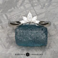 The "Vilaine" band in platinum with five white gemstones rests on a rough blue stone atop a textured gray surface, with the "Earth's Treasury" logo at the bottom.