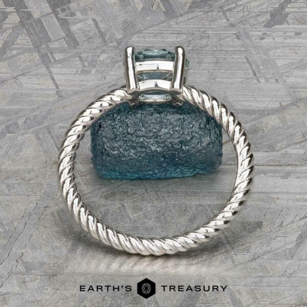 The "Winnie" ring in platinum with 0.95-carat Montana sapphire The "Winnie" ring, crafted in platinum with a 0.95-carat Montana sapphire, elegantly displayed on a textured blue-green surface like the soothing notes of music.