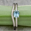 A twisting platinum band adorned with a 0.95-carat Montana sapphire is elegantly displayed on a green leaf, reminiscent of something the "Winnie" ring might cherish.