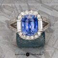 The Vintage Halo Ring with a 5.09-Carat Ceylon Sapphire in 18k White Gold features a stunning centerpiece surrounded by smaller diamonds on a textured surface, with "Earth's Treasury" elegantly inscribed at the bottom.