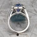 This exquisite vintage halo ring features a stunning 5.09-carat Ceylon Sapphire set in prongs, beautifully displayed on an 18k white gold textured surface. At the bottom, the logo proudly reads "Earth's Treasury.