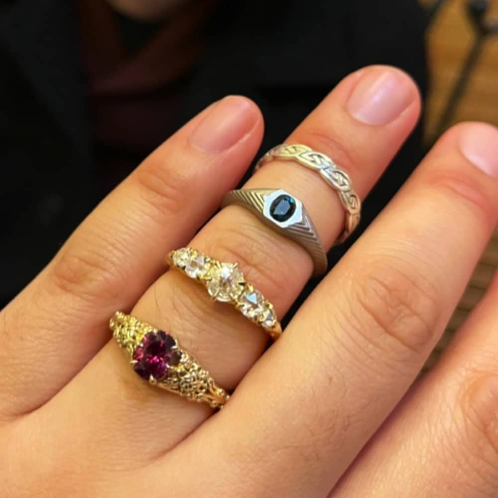 A photo from a customer review featuring the "Guanyin" ring and the "Gawain" ring alongside two more of the customer's non-Earth's Treasury rings.