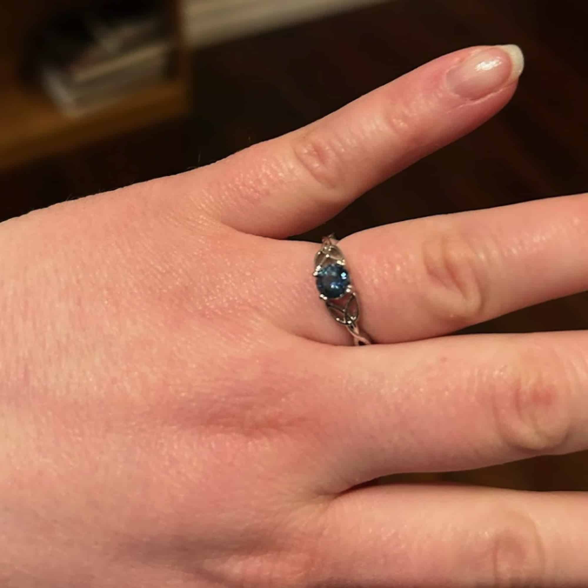 A photo from a customer review featuring a white gold "Saoirse" ring with a round blue Montana sapphire