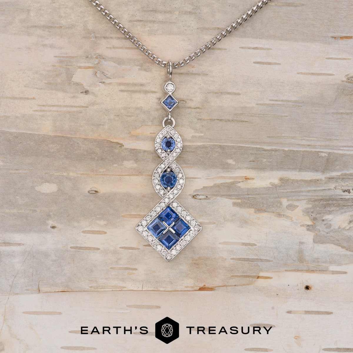 A studio shot of a custom pendant featuring diamonds and yogo sapphires.