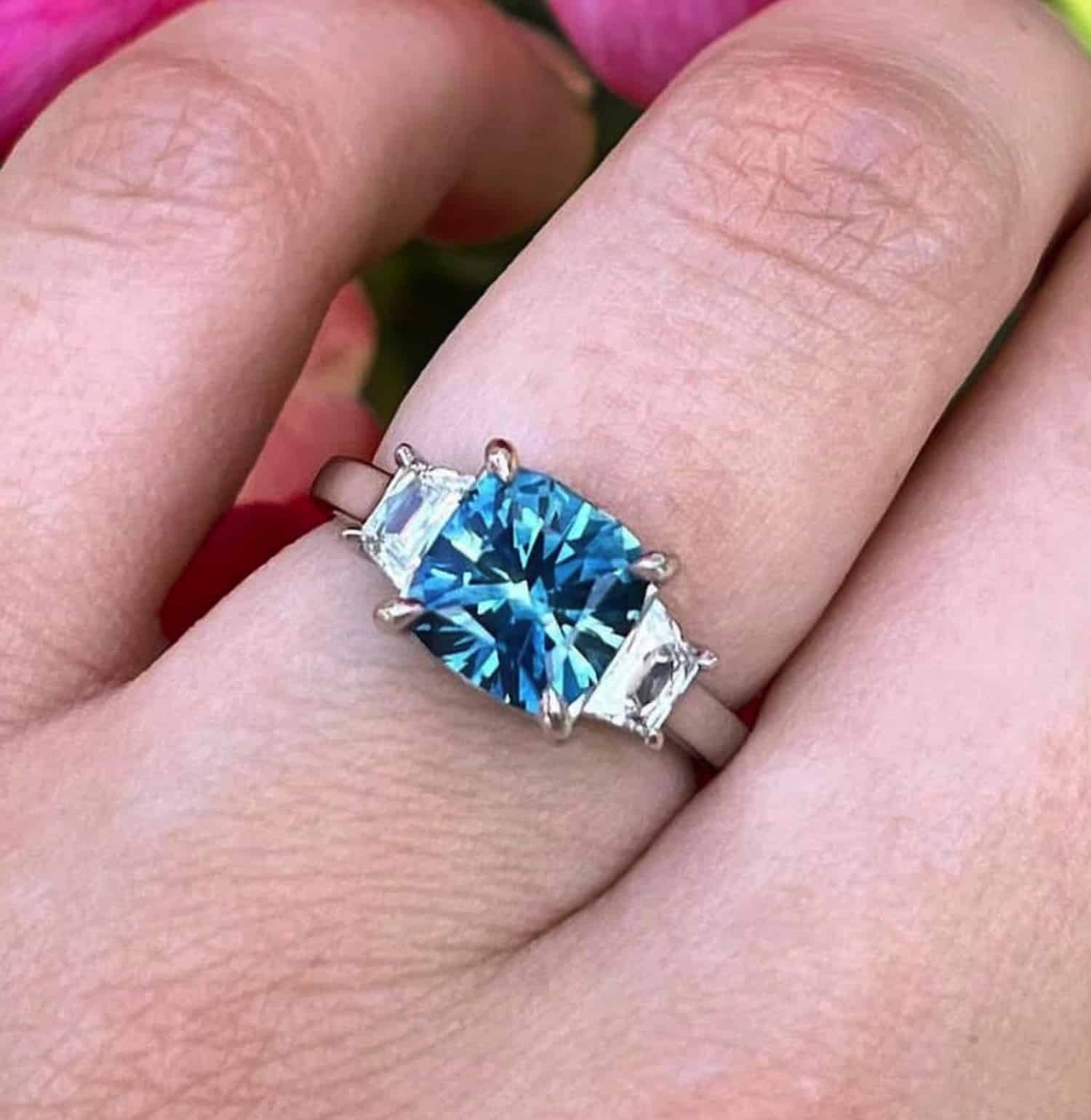A photo from a customer review featuring a platinum "Damara" ring with a square teal Montana sapphire