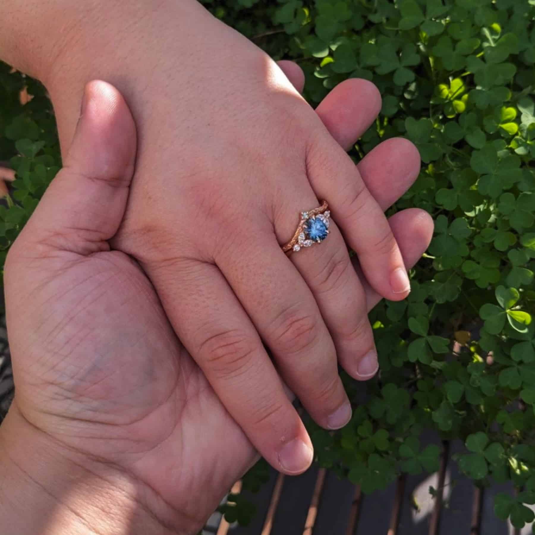 A photo from a customer review featuring a "Cattleya" ring in 14k rose gold with 1.89-carat Montana sapphire, alongside the "Passiflora" band in 14k rose gold