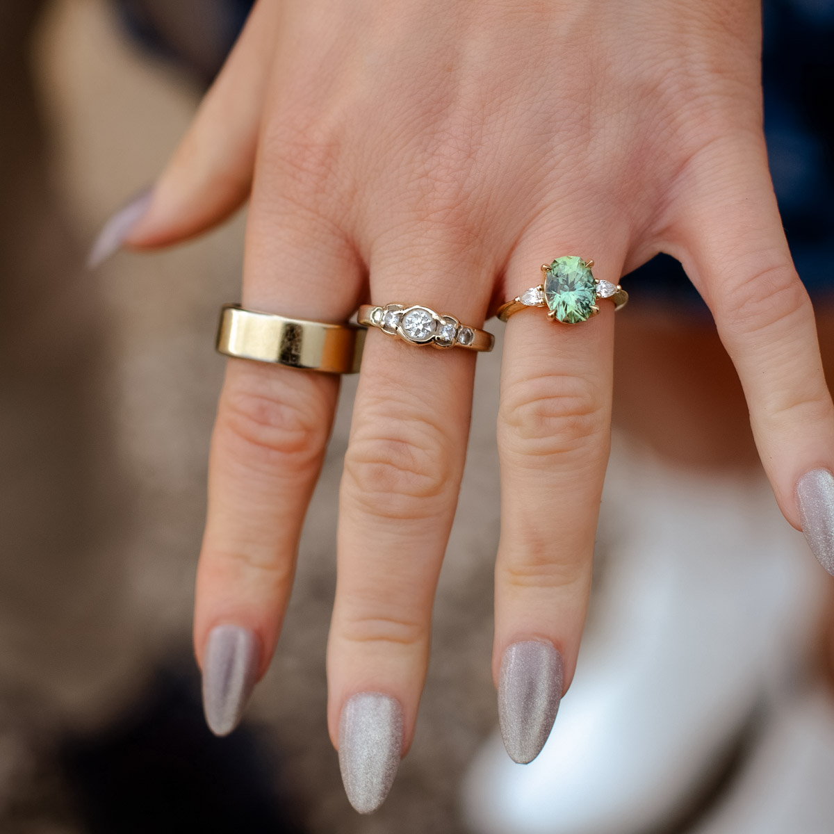 Two rings not made by Earth's treasury, then on the right: a custom three stone ring in 14k yellow gold with a 3.50-Carat Montana Sapphire