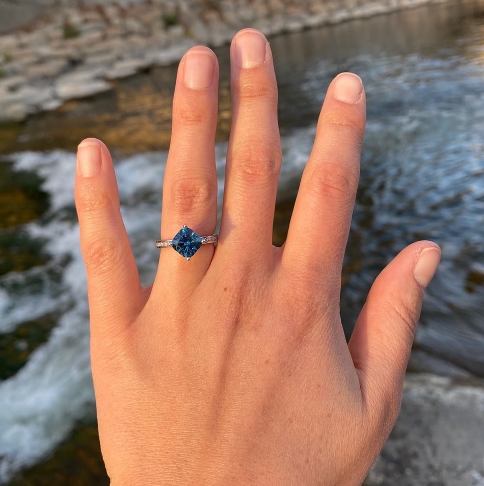 A photo from a customer review featuring a hand wearing The Classic Channel-Set "Kira" Ring in 14k white gold with 2.93-carat Montana sapphire