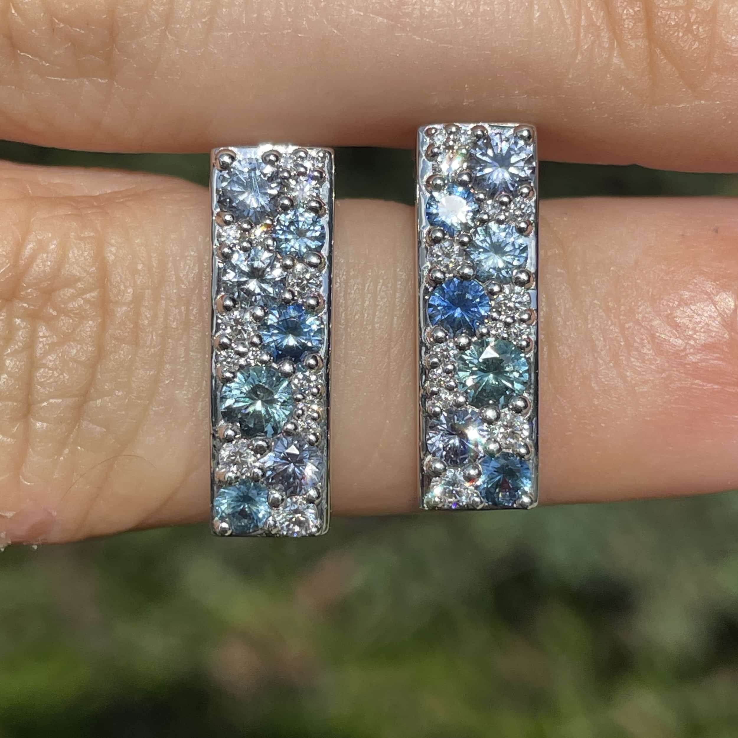 A photo of a pair of custom earrings featuring clusters of micro pave-set diamonds and sapphires.