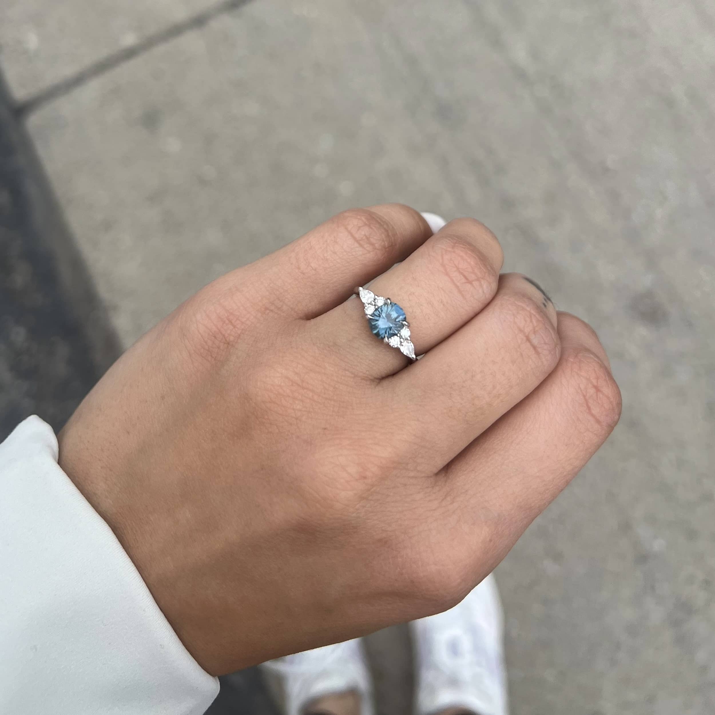 A photo from a customer review featuring a hand wearing a "Vela" ring in platinum with 1.68-carat Montana sapphire