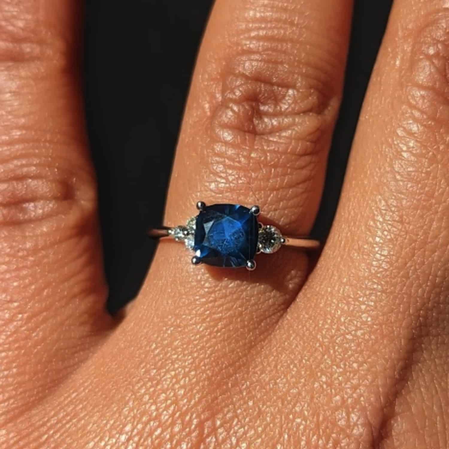 A photo from a customer review featuring a platinum "Erythia" ring with a blue square sapphire