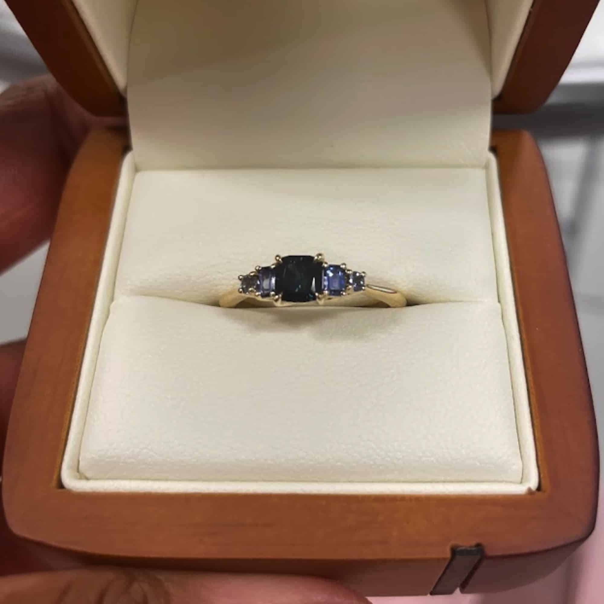 A photo from a customer review featuring a custom five-stone ring in 14k yellow gold with a 0.64-carat Montana sapphire