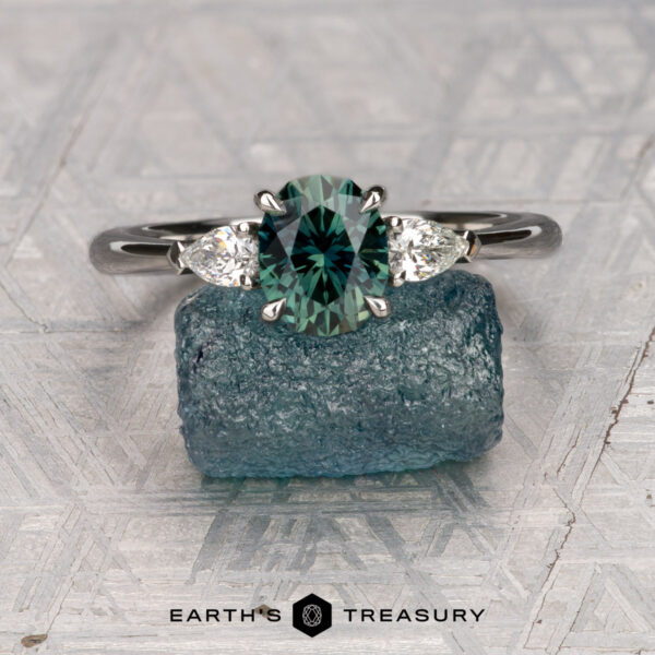 The Cathedral "Merope" ring in platinum with 1.36-carat Australian sapphire The Cathedral "Merope" ring in platinum features a 1.36-carat Australian sapphire center stone flanked by two pear-shaped clear stones, shown atop a rough blue crystal with the Earth’s Treasury logo below.