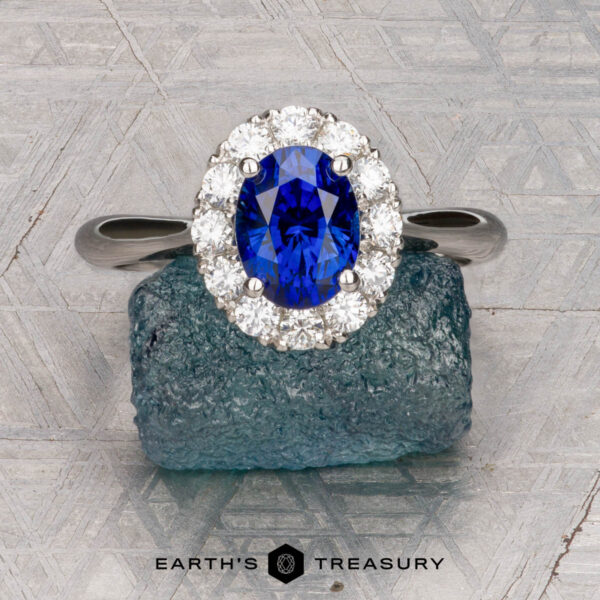 The Pave "Valeria" ring in platinum with 1.41-carat Ceylon sapphire The Pave "Valeria" ring in platinum features a 1.41-carat Ceylon sapphire and pave-set diamonds, shown on a rough blue stone with engraved patterns in the background.