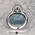 The Pave "Valeria" ring in platinum features a 1.41-carat Ceylon sapphire and pave-set diamonds, shown on a rough blue stone with engraved patterns in the background.