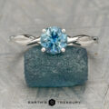 The "Lynet" ring in platinum with a 1.05-carat Montana sapphire is displayed on a rough blue mineral, with the "Earth's Treasury" logo and text below.