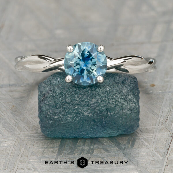 The "Lynet" ring in platinum with 1.05-carat Montana sapphire The "Lynet" ring in platinum with a 1.05-carat Montana sapphire is displayed on a rough blue mineral, with the "Earth's Treasury" logo and text below.