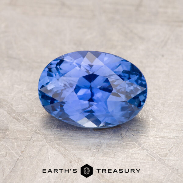 A 1.83-carat oval-cut Ceylon sapphire, featuring intricate facets, is showcased against a textured background. Text at the bottom center of the image reads "EARTH'S TREASURY.