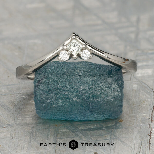The "Sappho" band in platinum A platinum "Sappho" band rests atop a rough blue gemstone, featuring Earth's Treasury branding at the bottom.