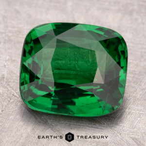 A dazzling square-cut green gem, the 5.02-Carat Tsavorite Garnet, rests on a textured background with "Earth's Treasury" stylishly displayed beneath it.
