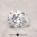 A pear-shaped 1.36-carat diamond with a faceted cut rests on a textured surface.
