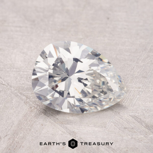 1.36-Carat Daimond A pear-shaped 1.36-carat diamond with a faceted cut rests on a textured surface.