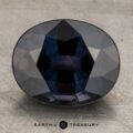 A 3.10-carat, faceted, oval-shaped Bluish Violet to Purple Color-Change Sapphire is displayed against a textured, silver-gray background. The gemstone displays various shades of blue under the lighting, and the text "EARTH'S TREASURY" is printed at the bottom center.